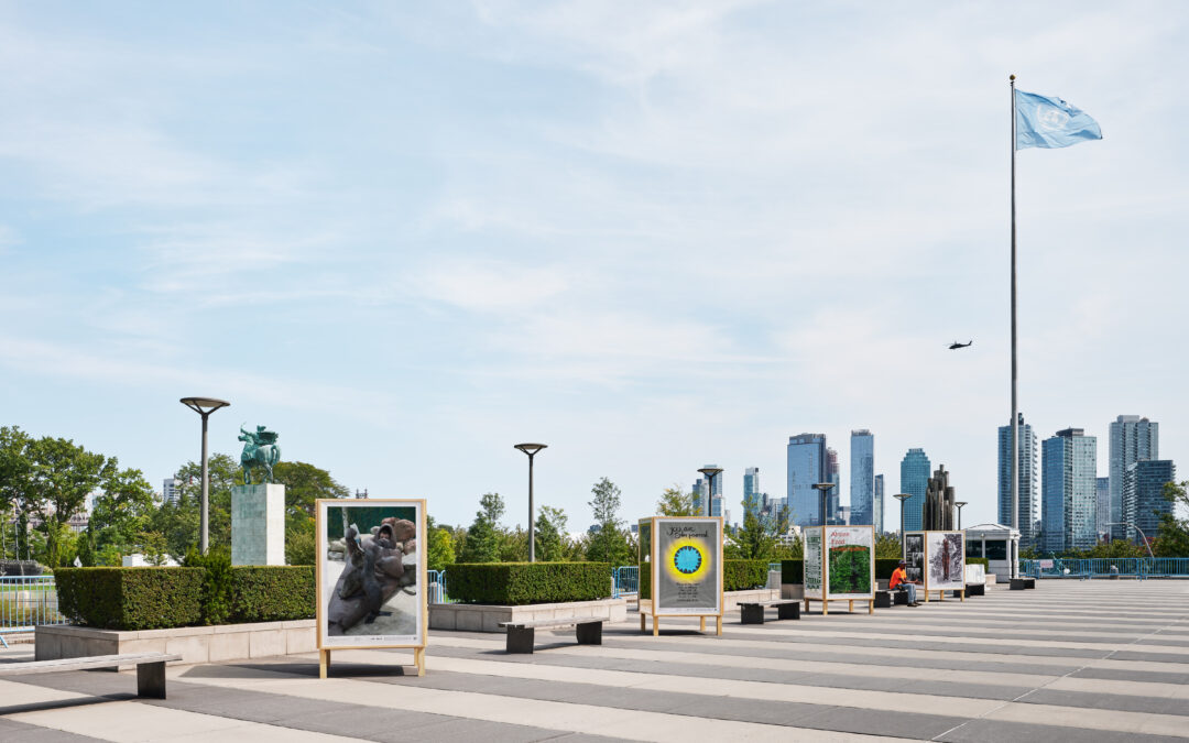 Outdoor art exhibition near city skyscrapers and flag.