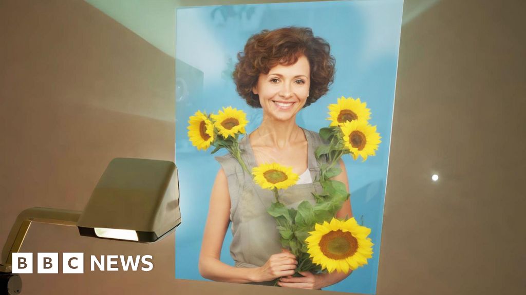 Woman smiling with sunflowers on BBC News.