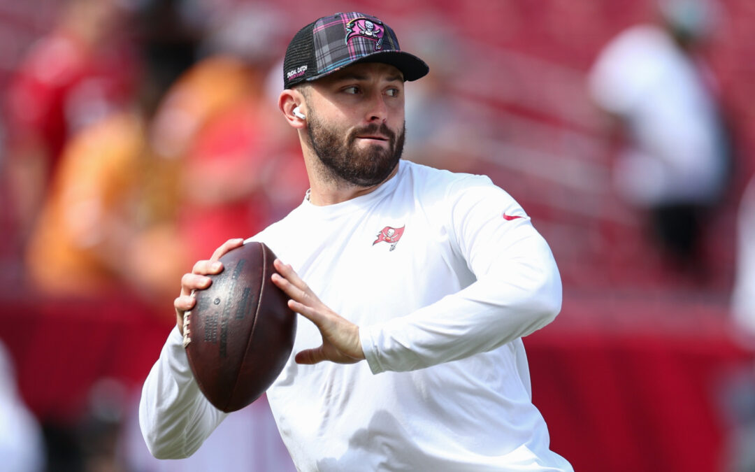 Football player practicing throw, stadium background.