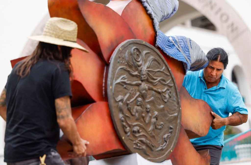 Two men move a large ornate sculpture