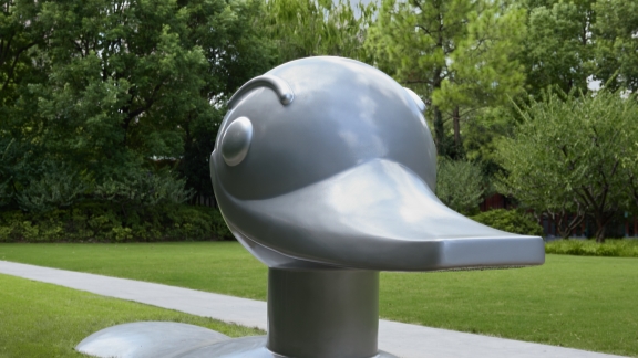 Large metallic duck sculpture in a park