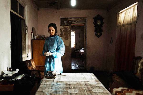 Person in protective gown in dimly lit room.