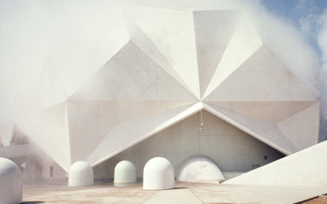 Geometric white pavilion with surrounding artwork.