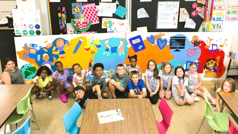 Kids posing in front of classroom mural.