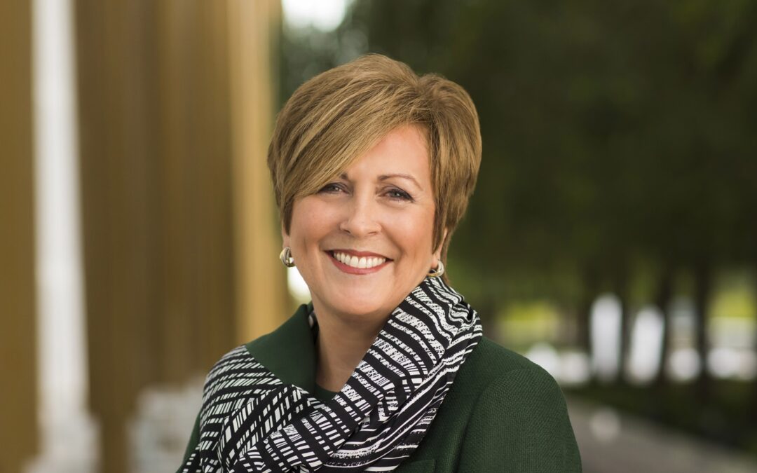 Smiling woman in green coat outdoors.