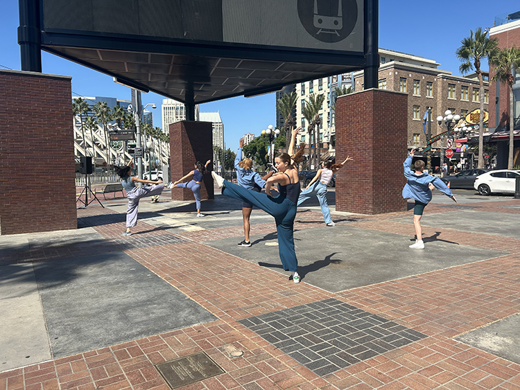 People practicing dance moves in urban plaza.