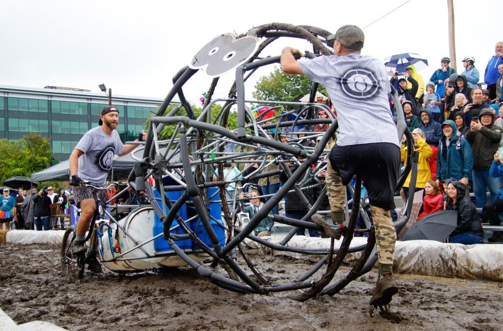 Participants at outdoor mud festival with metal sculpture