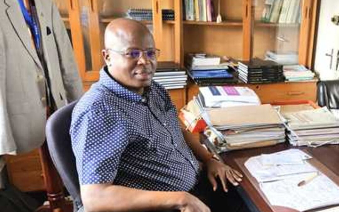 Man sitting at cluttered office desk.