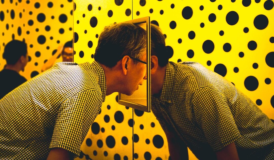 Person looks into mirror with polka dot background.