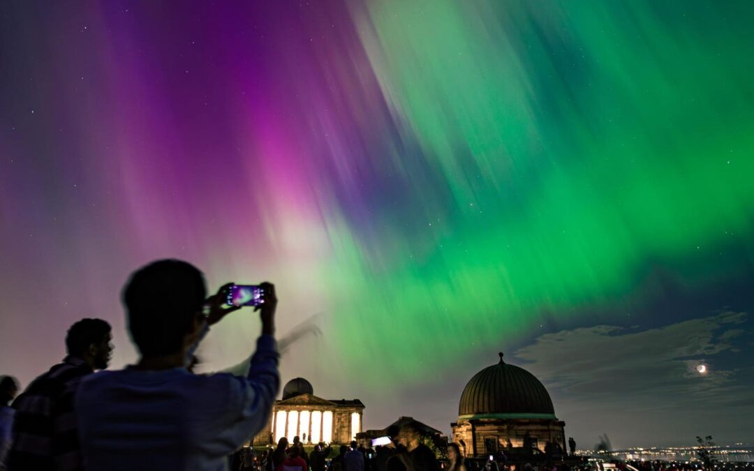 People photographing vibrant northern lights at night