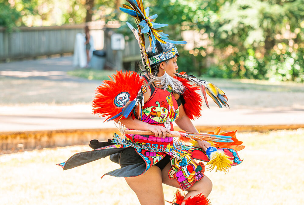 Person performing traditional indigenous dance outdoors.