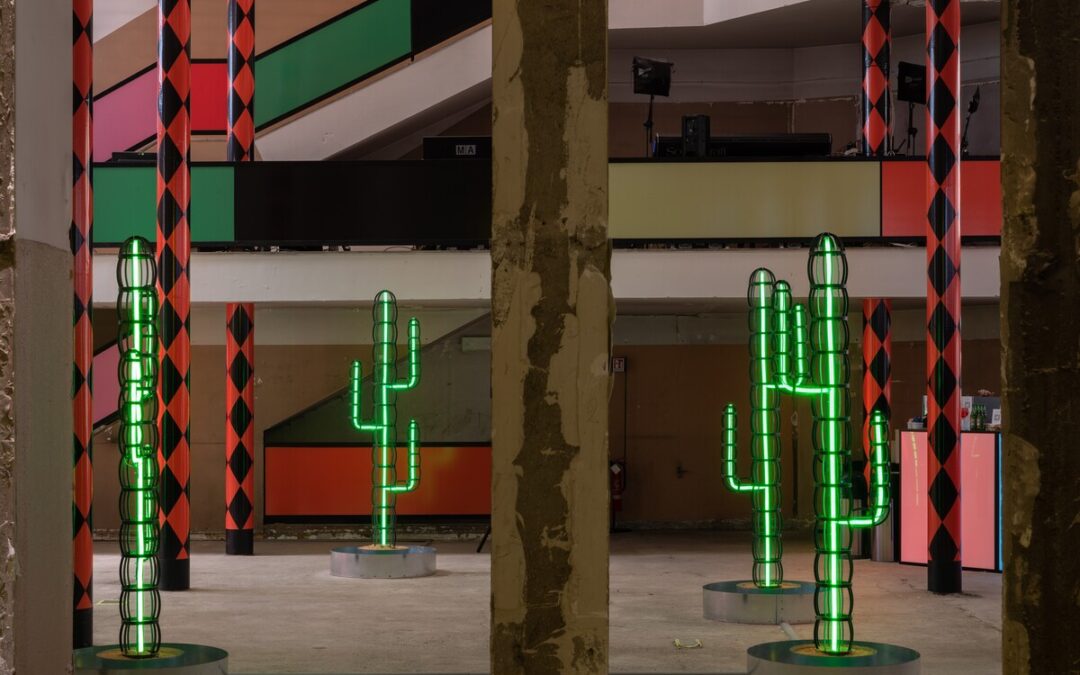 Neon cactus sculptures in colorful interior space.