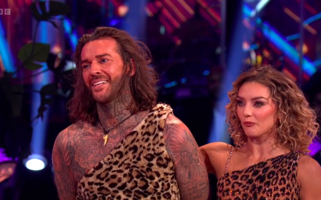 Dancers wearing leopard print costumes, smiling on stage.