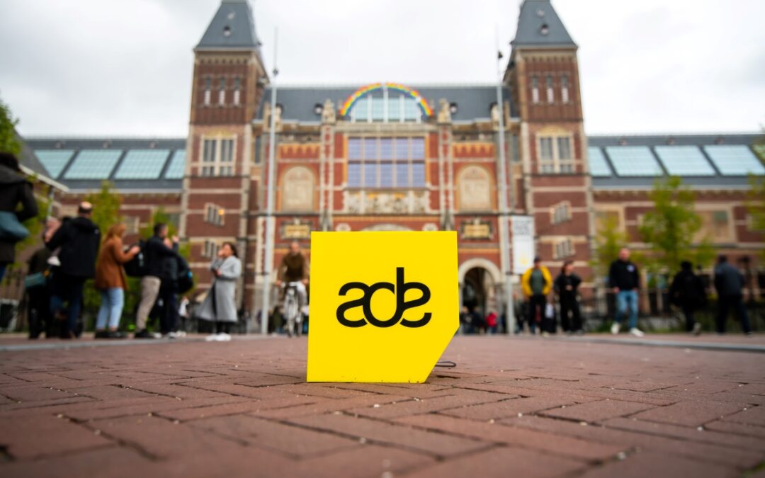 ADE sign in front of building, people around.