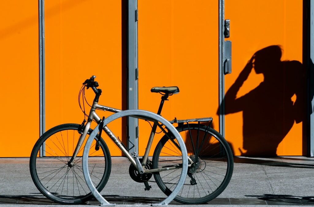 Bicycle parked with shadow on orange wall.