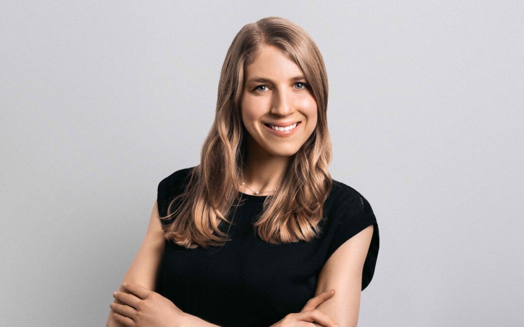 Smiling woman with crossed arms in black shirt.