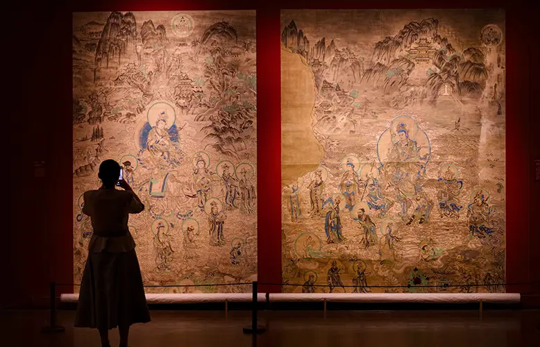 Person photographs intricate Asian art exhibit display.