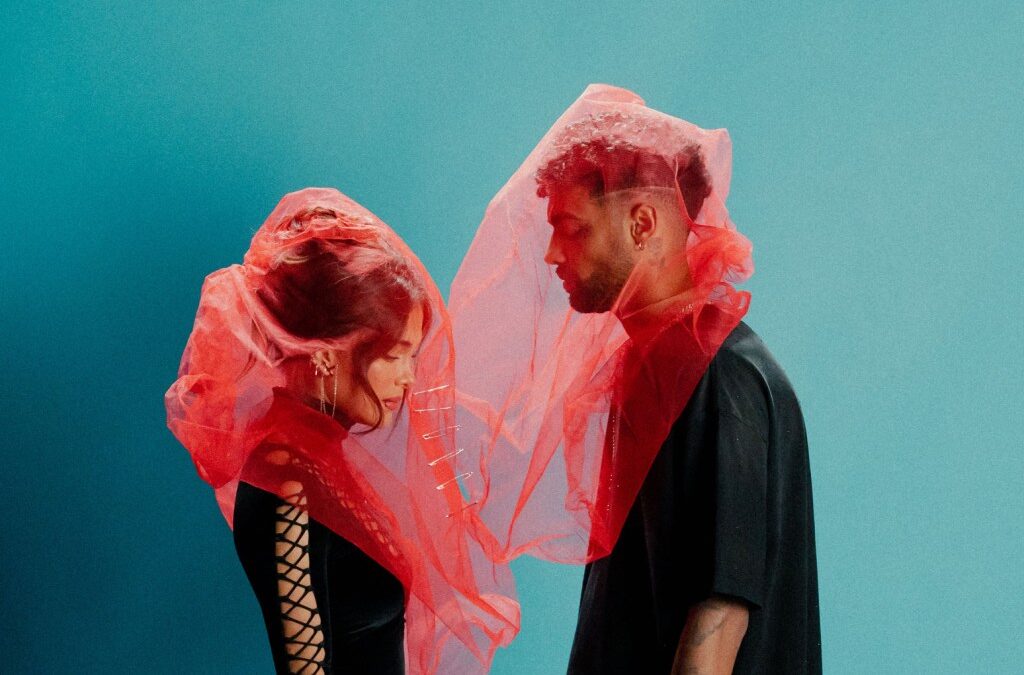 Two people in red veils, blue background.