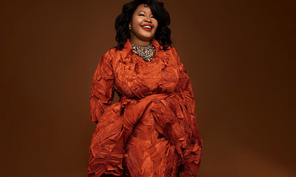 Smiling woman in orange textured outfit.