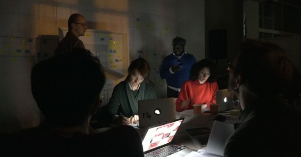 Group working late with laptops in dim lighting.