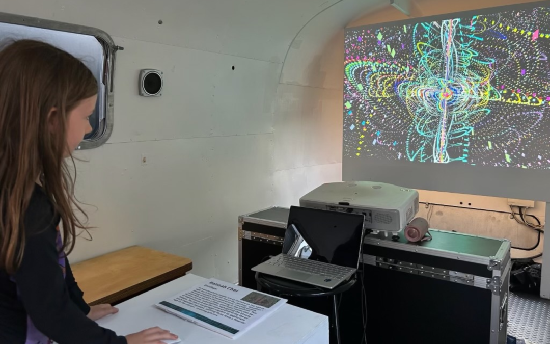 Girl observes interactive colorful digital art projection.