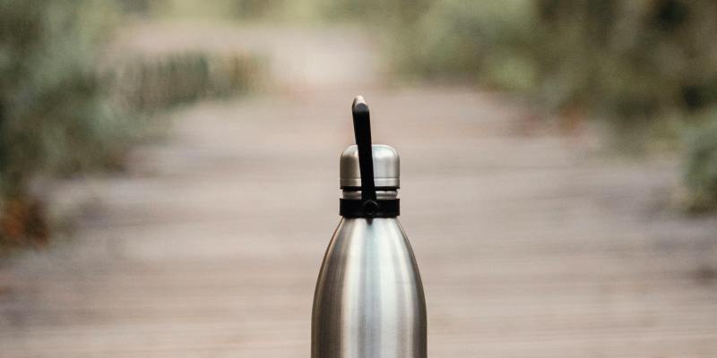 Stainless steel water bottle on outdoor path.
