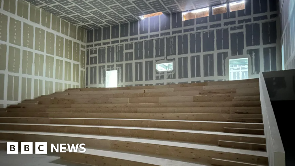 Unfinished auditorium with tiered wooden seating