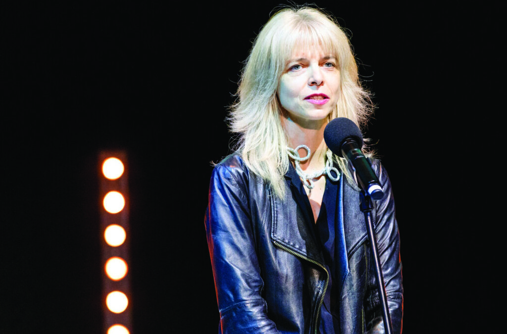 Woman speaking on stage with microphone.