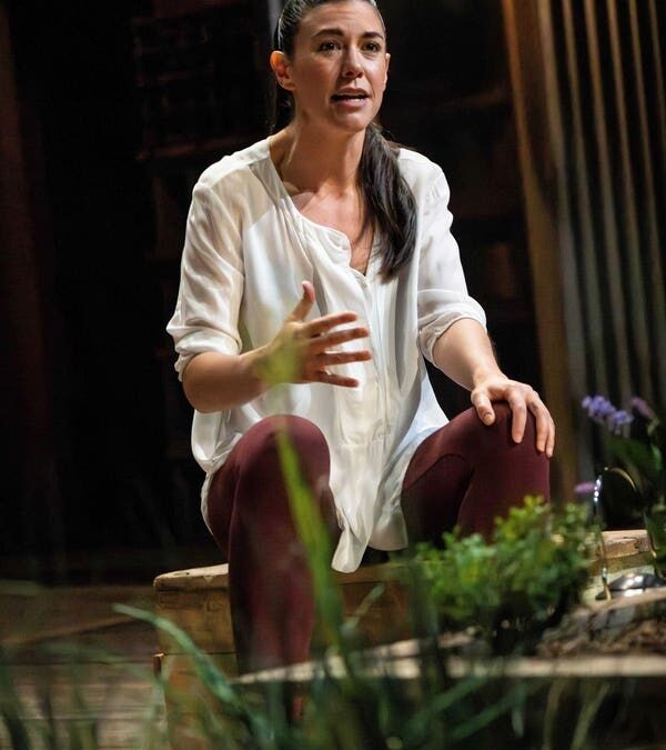 Woman speaking on stage with plants around her.