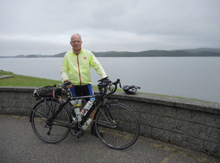 Cyclist with bike by a scenic lake view.