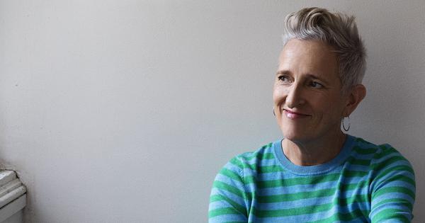 Smiling person in green and blue striped shirt.