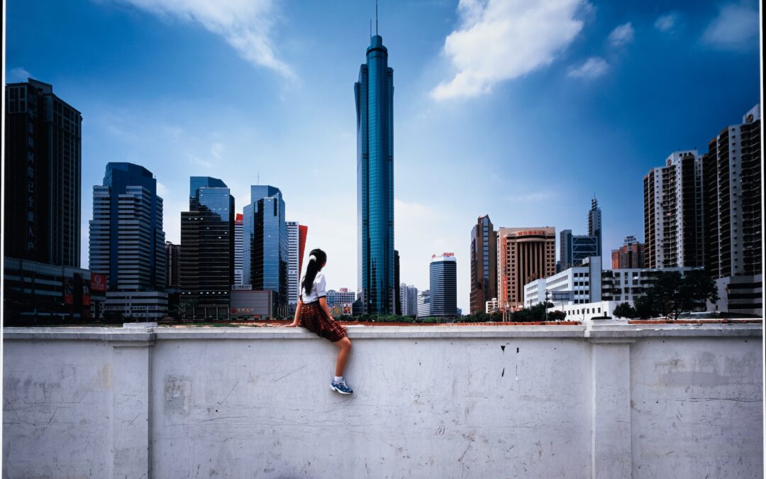 Person sitting on wall in urban skyline