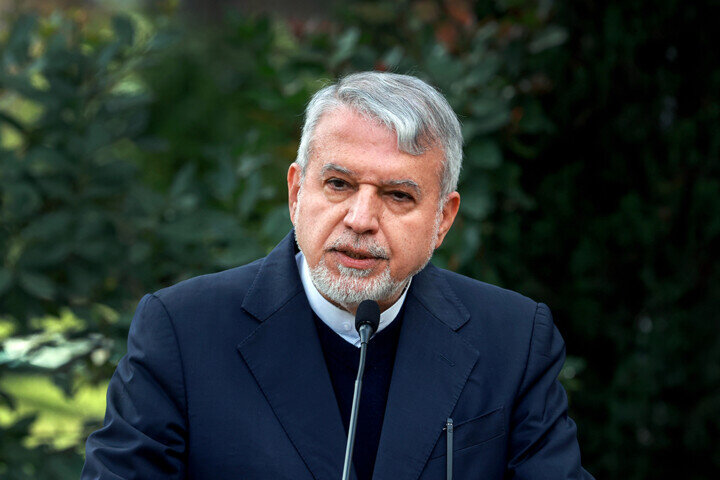 Man speaking at outdoor event with microphone.