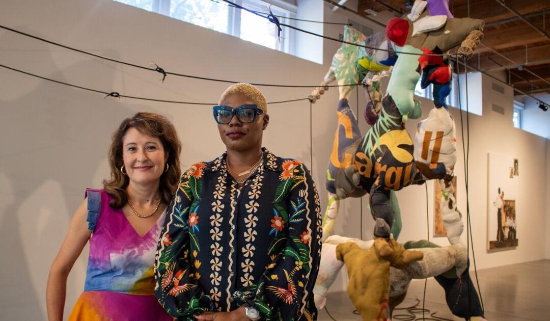 Two women standing in colorful art gallery.
