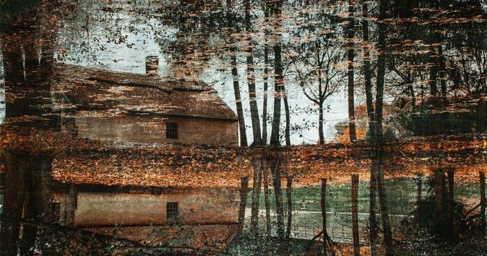 Rustic house surrounded by autumn trees reflection.