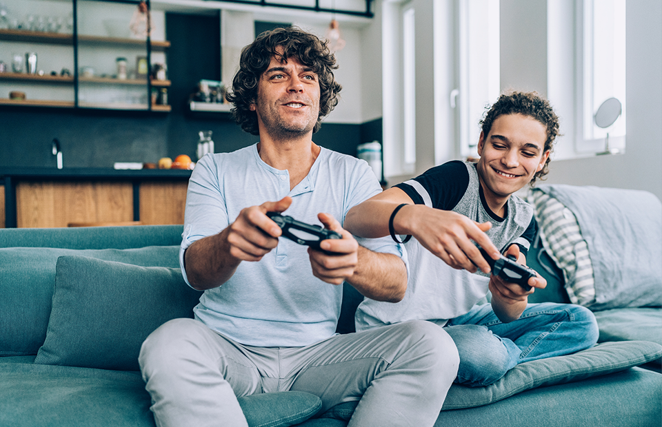 Father and son playing video games on couch.