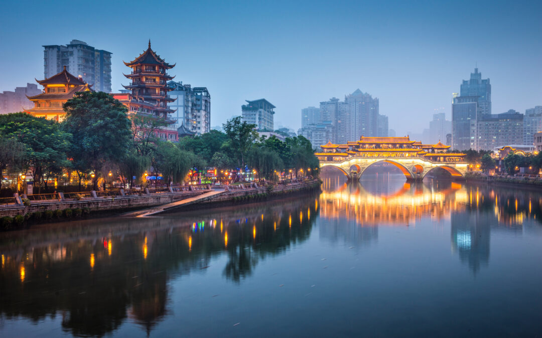 Illuminated bridge and buildings in Chengdu at dusk.