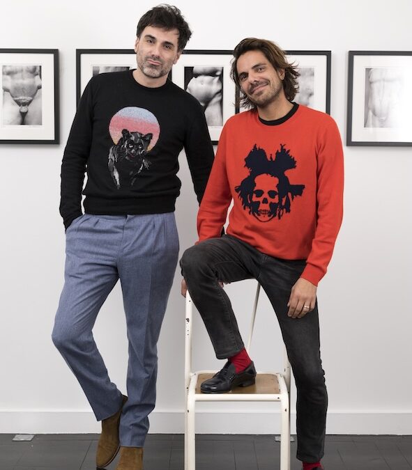 Two men posing by black and white photos.