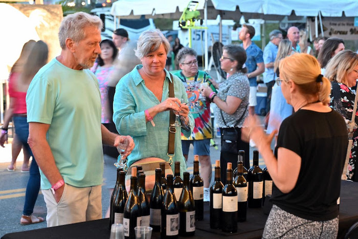People tasting wine at outdoor event.