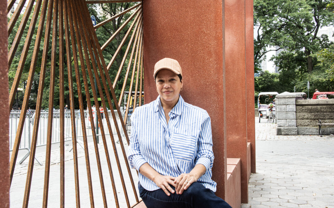 Woman seated by outdoor sculpture in park.