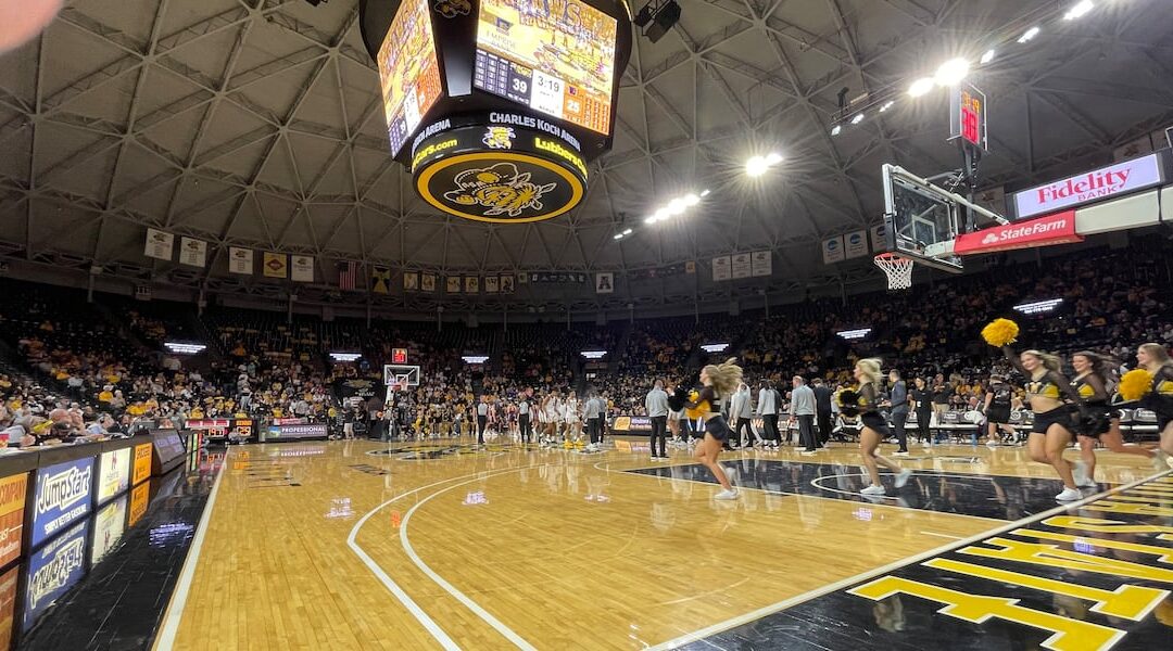 Cheerleaders perform during basketball game at arena.