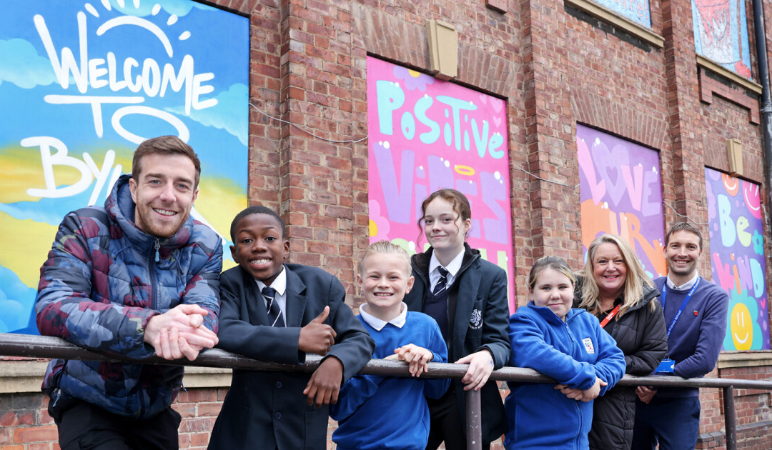 Group smiling in front of colorful graffiti wall.