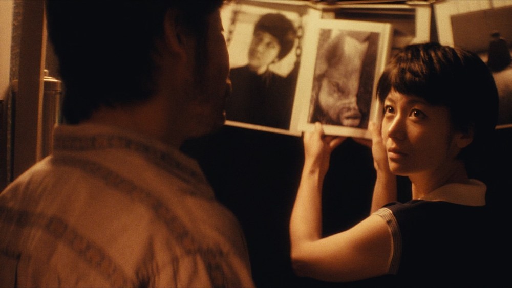 Woman showing man photo album in dim light.