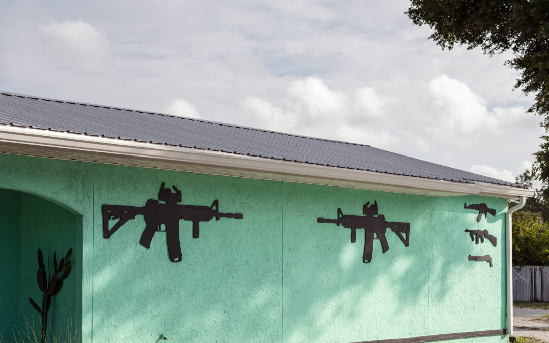 Green building with black gun silhouettes on wall.