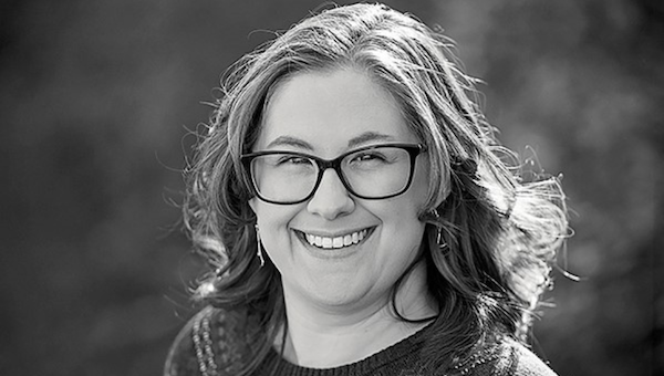 Smiling person wearing glasses, outdoor portrait.