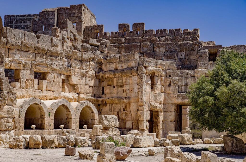 Ancient stone ruins with arches, tree nearby.