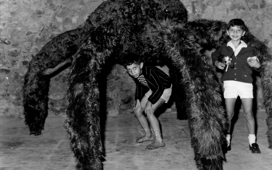 Children playing under giant spider sculpture