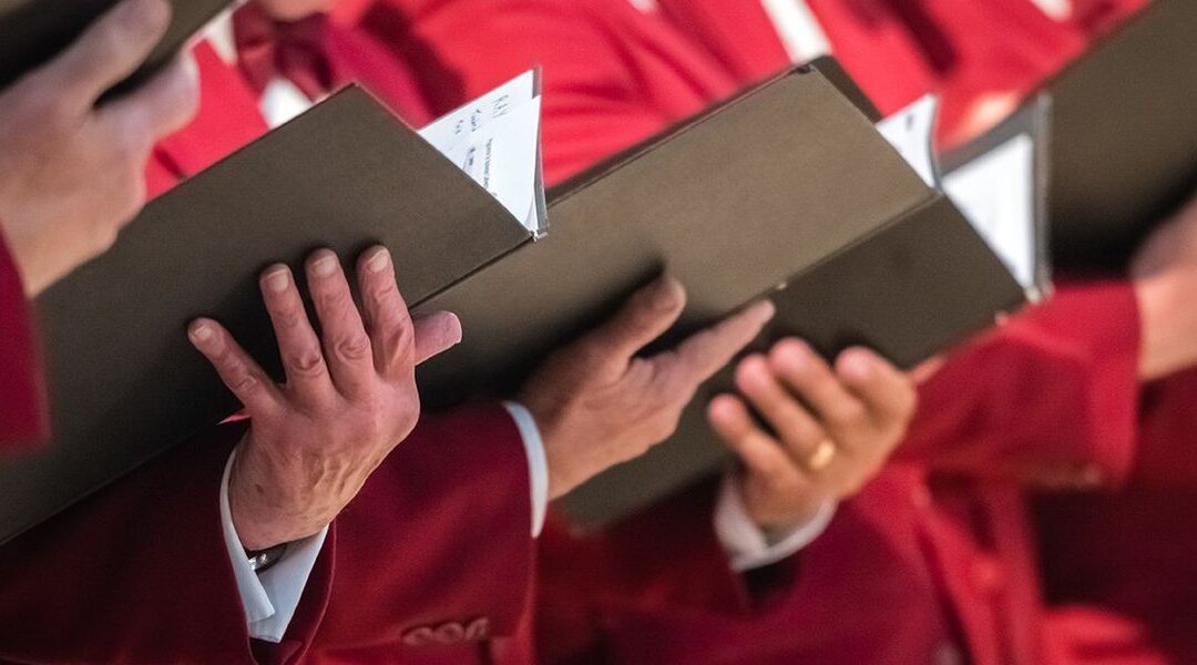 Choir members holding black music folders.