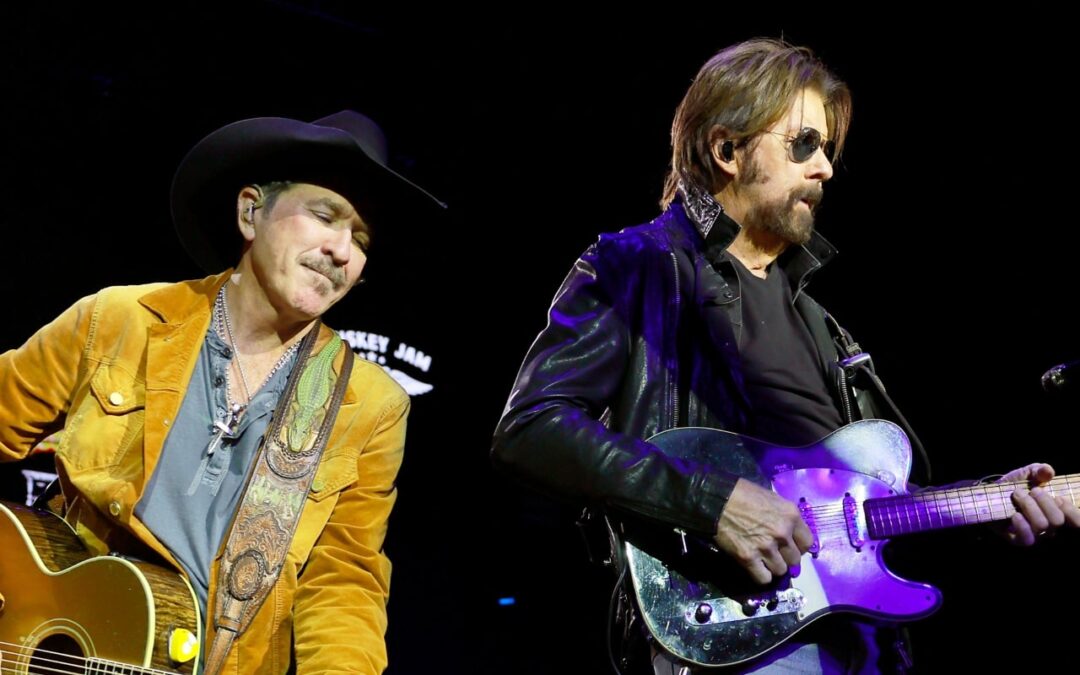 Two musicians performing with guitars on stage.