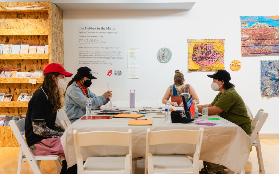 People working at a table in an art exhibit.